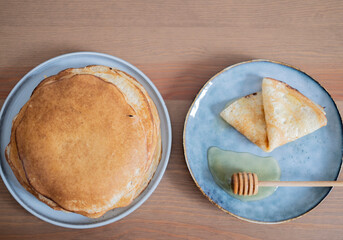 pancakes with honey on blue plate on wooden table, breakfast concept