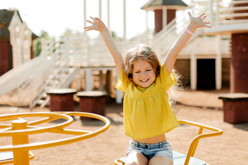 A charming little girl is walking in the park, swinging on a swing. Happy childhood, playtime - Powered by Adobe