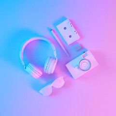 Creative layout made of vintage camera, headphones and music cassette in vibrant gradient holographic neon colors. Flat lay. Concept art. Minimal summer surrealism.