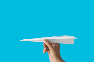 White paper airplane in the hand on a blue background with copy space.Travel concept