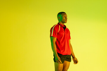 African american male rugby player over yellow lighting