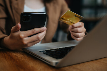 Hands holding smartphone and using credit card at home office. Online shopping.