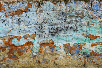 the surface of an old clay wall, weathered layers crumble, painted in different colors, for background or texture, an old house in the village