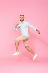Fototapeta na wymiar man in summer clothes jumping on pink background.