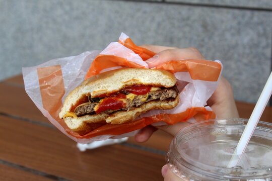 In a cafe at the table, a woman's hand holds a bitten sandwich.