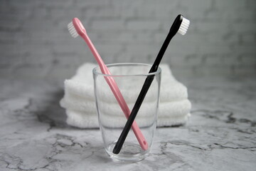 ピンク黒の歯ブラシとコップとタオルと大理石の洗面台の中央配置の写真