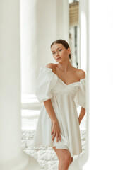 A young beautiful woman in a white dress near the columns
