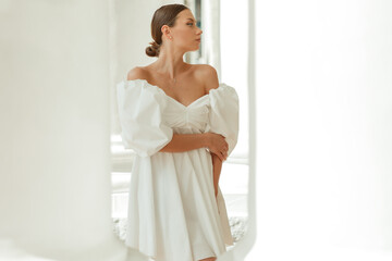 Fototapeta premium A young beautiful woman in a white dress near the columns