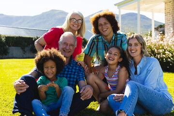 Portrait of cheerful multigeneration multiracial family enjoying leisure time in yard on sunny day