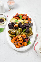 Various roasted vegetables on white dish. Top view, flat lay, copy space.