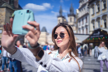 Obraz premium Woman taking selfie on instant camera on street