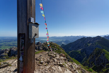 On top, summit cross with Tibetan prayer flags on the Aggenstein in the Tannheim Mountains, Austria.