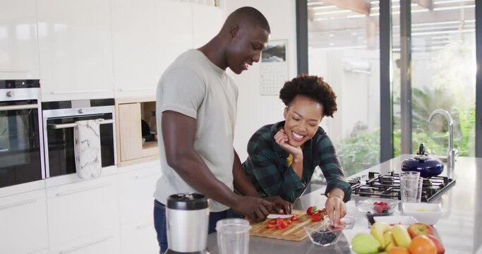 Video of happy african american couple preparing meal together in kitchen