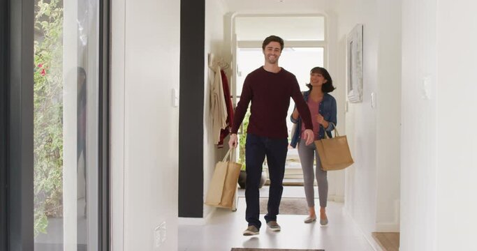 Video of happy diverse couple returning home with shopping bags