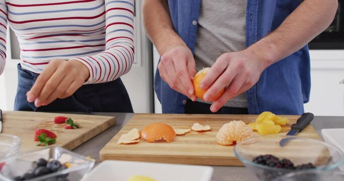 Video of midsection of diverse couple preparing fruits for juice