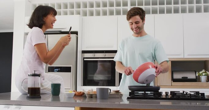 Video of happy diverse couple preparing breakfast together in kitchen
