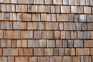 Facade cladding of weathered wooden shingles on a field barn in the Alps. Copy space for your design. Web banner. 