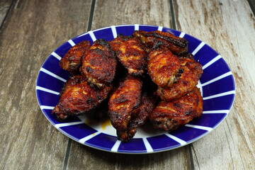 Traditional baked chicken wings dressing with chilly sauce serving on the plate. Famous appetizer menu in restaurant.