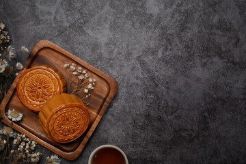 Above view Chinese moon cake for Mid Autumn festival and tea on rustic stone background with copy space