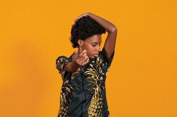 Young African American woman with short hair dressed in a summer shirt posing on an orange colored background