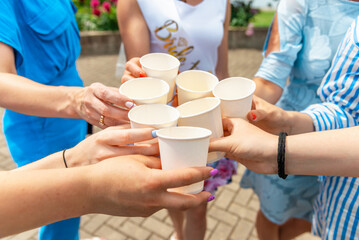 Girls celebrating a bachelorette party of bride.The girls party outdoors. Champagne or wine.Clinking paper cups with alcohol and toasting in bride party.Summer hot day.