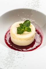 Panna cotta with raspberry jam, berries and mint on white plate. Food recipe background. Close up