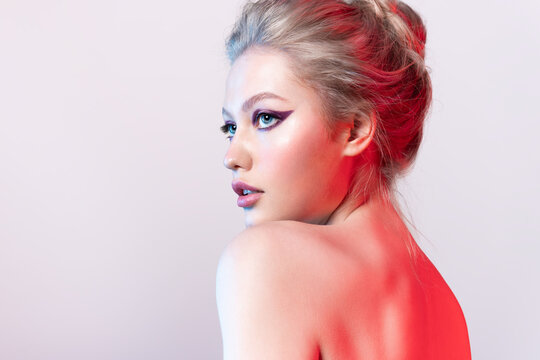 Pretty blonde young woman with  naked shoulders and fashionable make up with colorful arrows on eyes