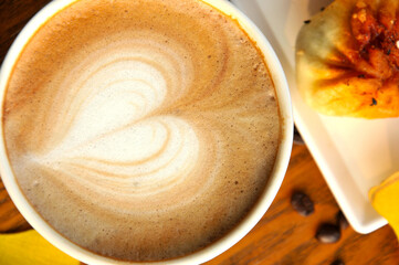 cup of coffee on wooden table and ginkgo leaf