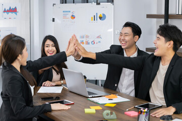 A group of young businessmen in suits, Asians, are determined and excited and delighted with their work. and encourage the team members by raising their hands happily concept teamwork