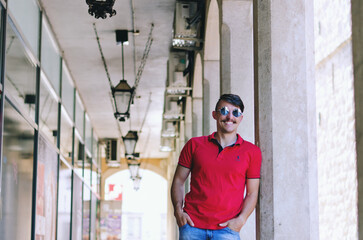 Fototapeta na wymiar Young happy handsome bearded man, tourist walking in old city of Koper. Summer vacation. Sunglasses. Lifestyle portrait