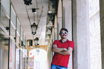 Obraz na płótnie Canvas Young happy handsome bearded man, tourist walking in old city of Koper. Summer vacation. Sunglasses. Lifestyle portrait