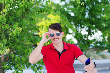 Young handsome man, tourist walking in summer park, old city. Phone call. Technology. Social media. Vacation