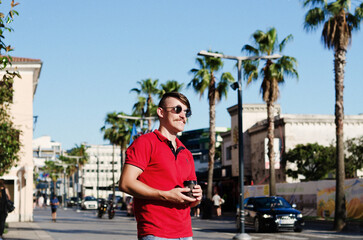 Young happy handsome bearded man, tourist walking in old city of Koper. drinking coffee. Summer vacation. palms. Sunglasses. Lifestyle 