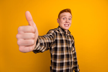 Photo of young cheerful man show thumb-up recommend feedback approve ads isolated over yellow color background