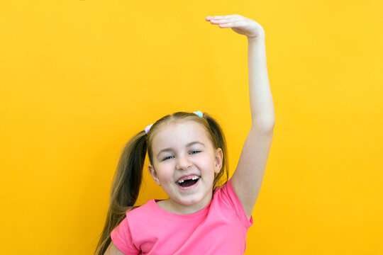 Little cute girl measuring her height on a yellow isolated background.