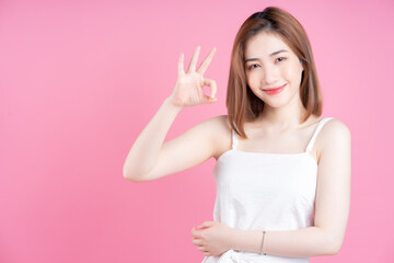 Image of young Asian woman posing on pink background