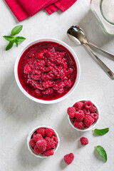 Delicious homemade raspberry jam in a bowl on a light table. Top view.