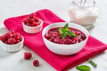 Raspberry jam in a bowl, fresh berries, mint leaves, sugar for making a berry dessert.