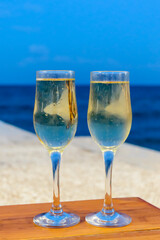 Two glasses with champagne against a sea in the evening, luxury resort with sea view, romantic vacation. Vertical view