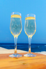 Two glasses with champagne at the beach ready for a toast. Vertical view