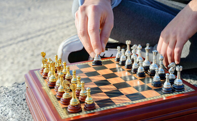 Outdoor chess game. Wooden chessboard with silver and gold pieces. Close-up