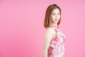 Photo of young Asian girl wearing flower dress on pink background