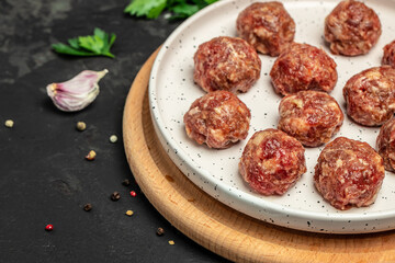 raw meatballs on wooden board, minced pork meat with spices on a dark background. Food recipe background. Close up