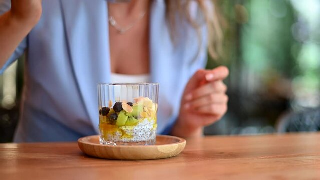 Woman eating chia pudding with fruits at a restaurant