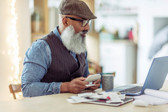 Mature man with beard paying bills at laptop