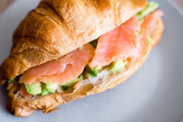 Fresh croissant with salmon and avocado. Healthy and tasty breakfast. Healthy diet. Close-up.
