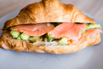 Fresh croissant with salmon and avocado. Healthy and tasty breakfast. Healthy diet. Close-up.
