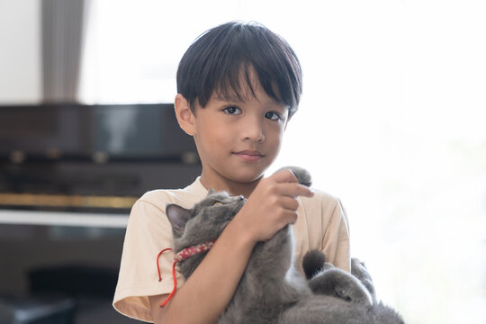Happy asian boy embracing cat at home. Boy playing with cat at home.