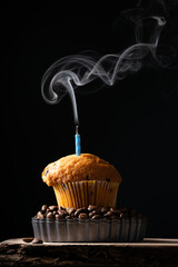 A coffee muffin with smoking candle on dark background, festive background, baking themes