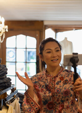 Female shop owner vlogging with smart phone in boutique